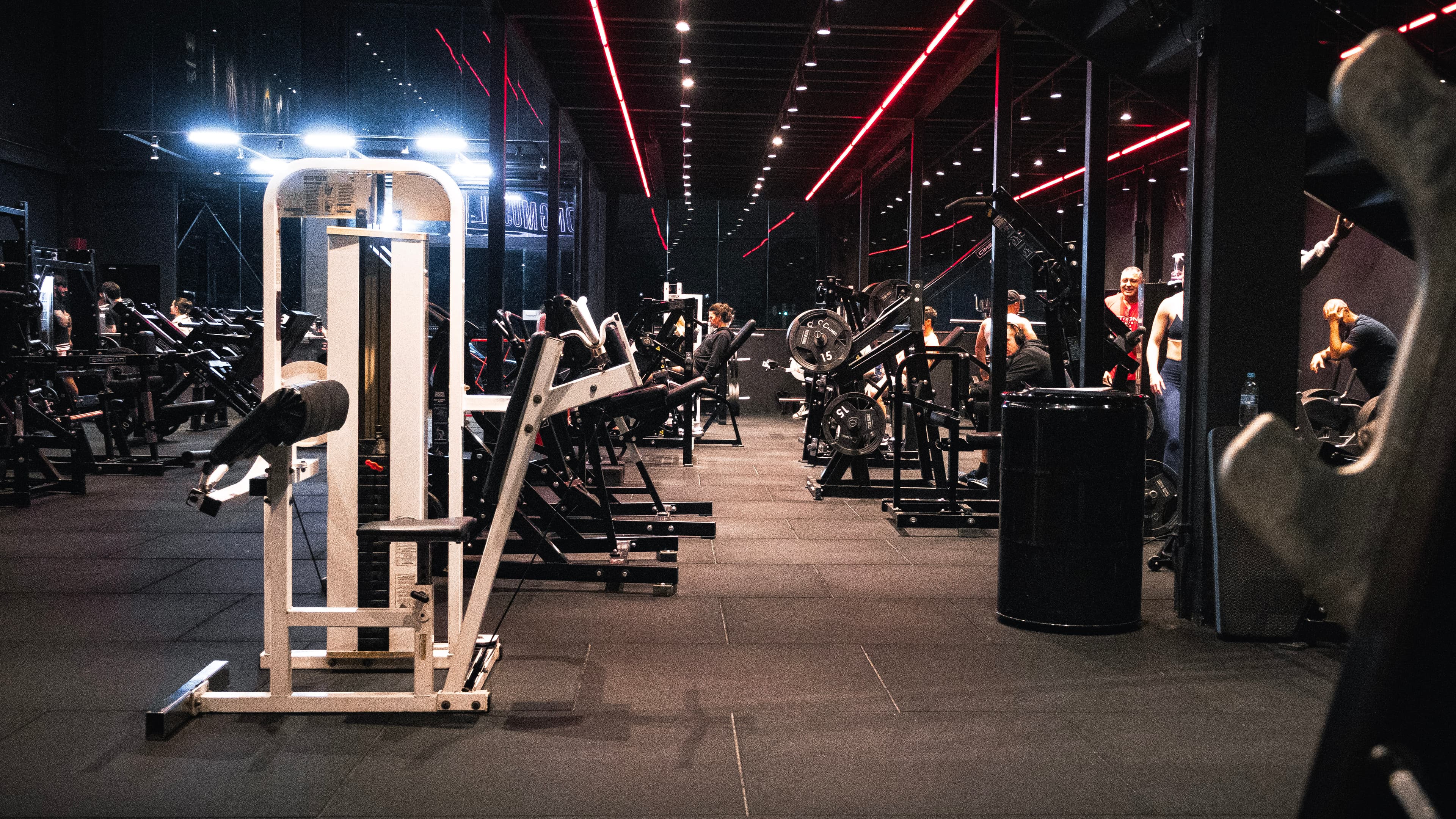 Salão de musculação da StrongClub com iluminação vermelha e equipamentos premium